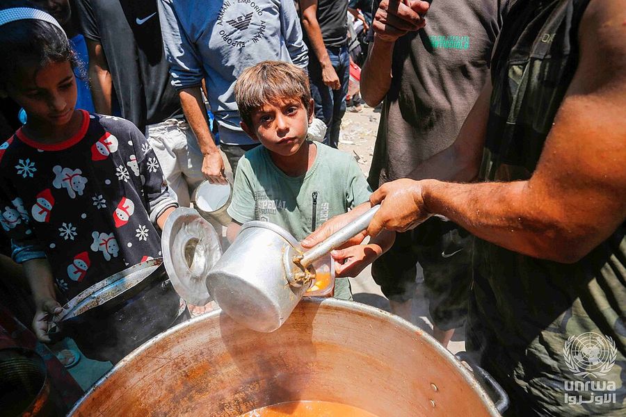A charity volunteer serves food to a boy in Deir el-Balah