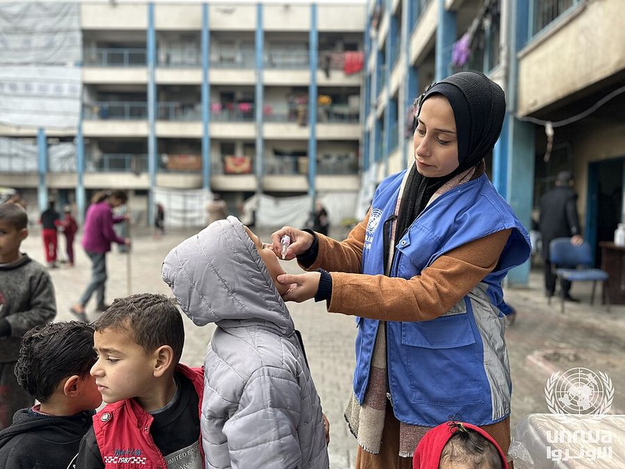 A health worker gives a child a polio vaccination at a school shelter in Beach camp